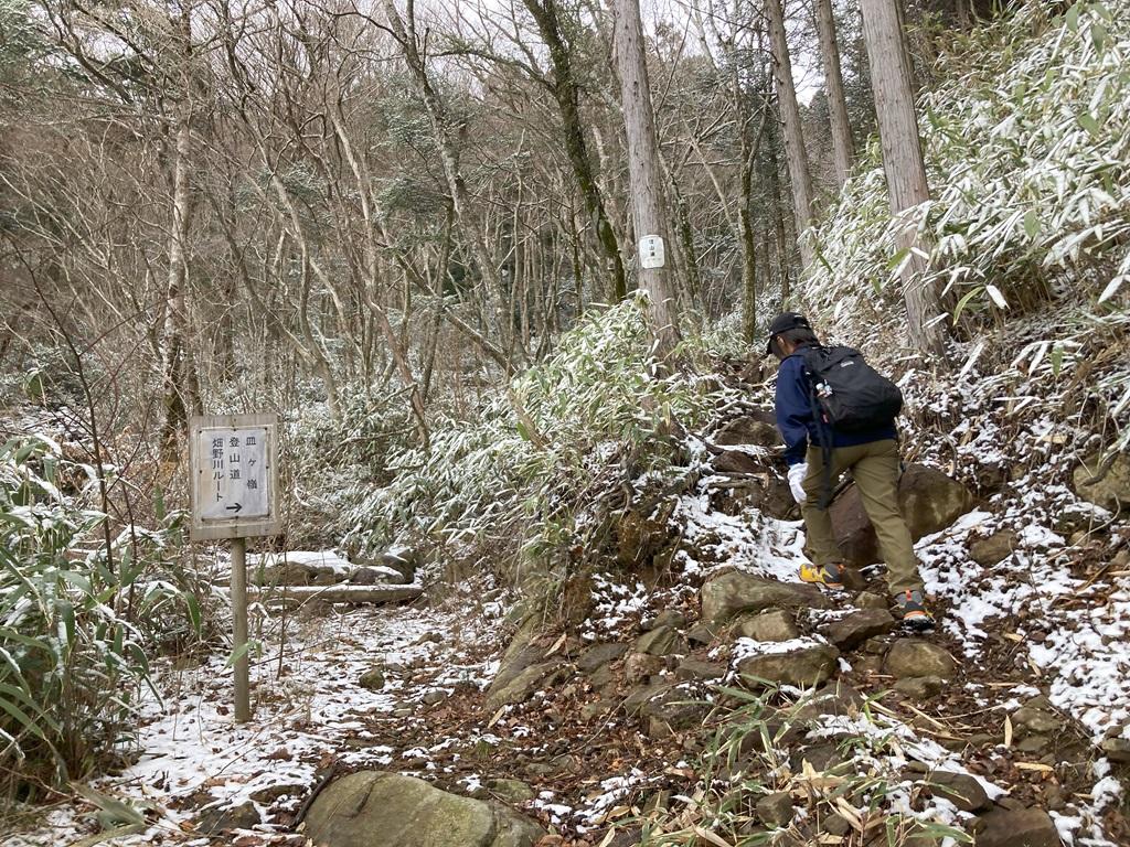 雪の山道を歩く娘、登山道の標識